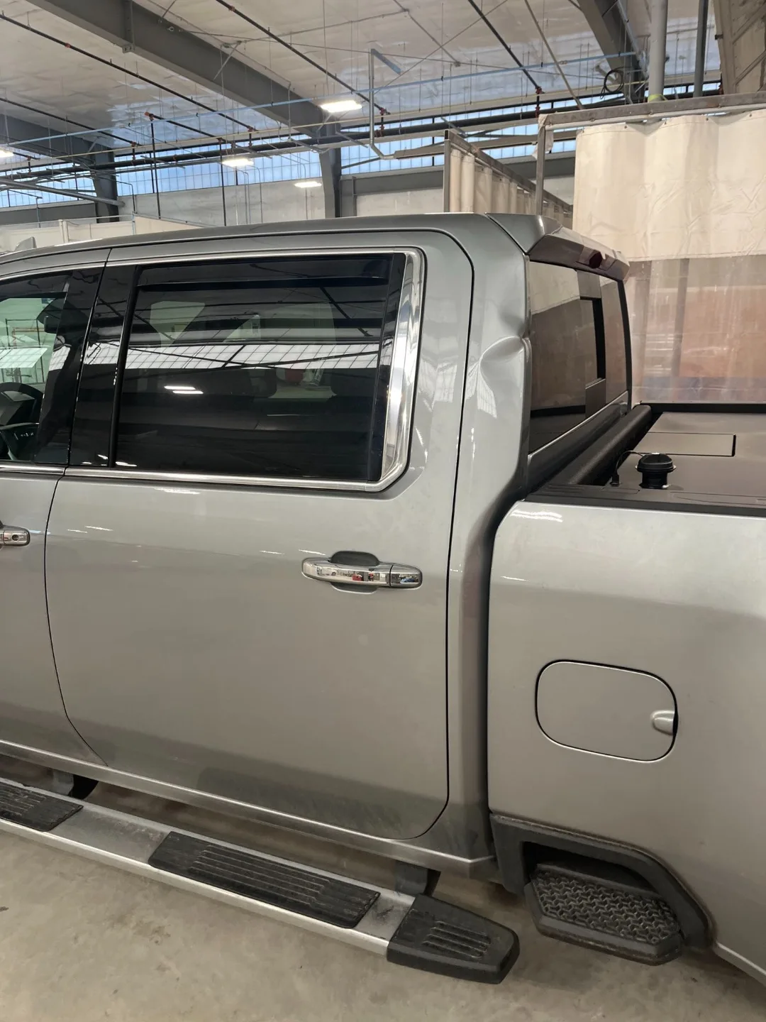 A GMC Sierra crew cab back together after collision repair, the refinished panels matched to the factory silver.