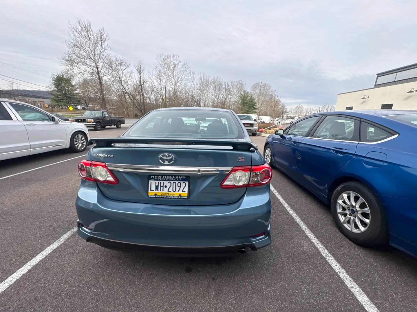 Blue Toyota Corolla S rear view in the parking lot after collision repair, rear bumper and panel restored with paint blended seamlessly
