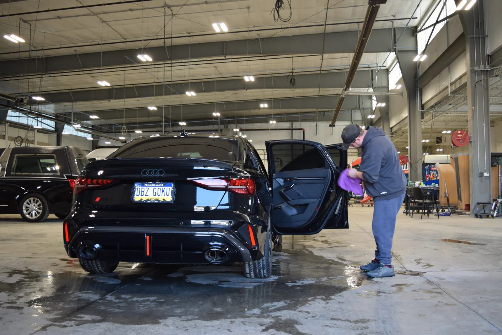 Heritage technician finishing the door interior of a black Audi RS3 sedan in the detail bay