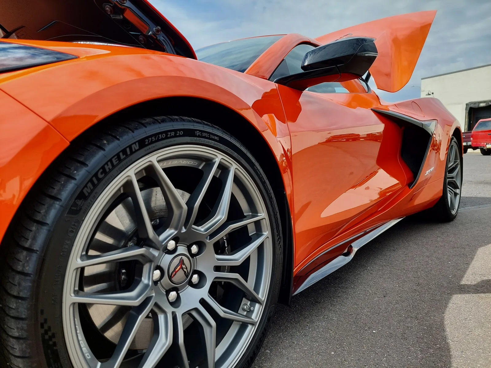Detail shot of orange Corvette C8 Z06 side rocker, Michelin tire and Corvette wheel, deep gloss flake