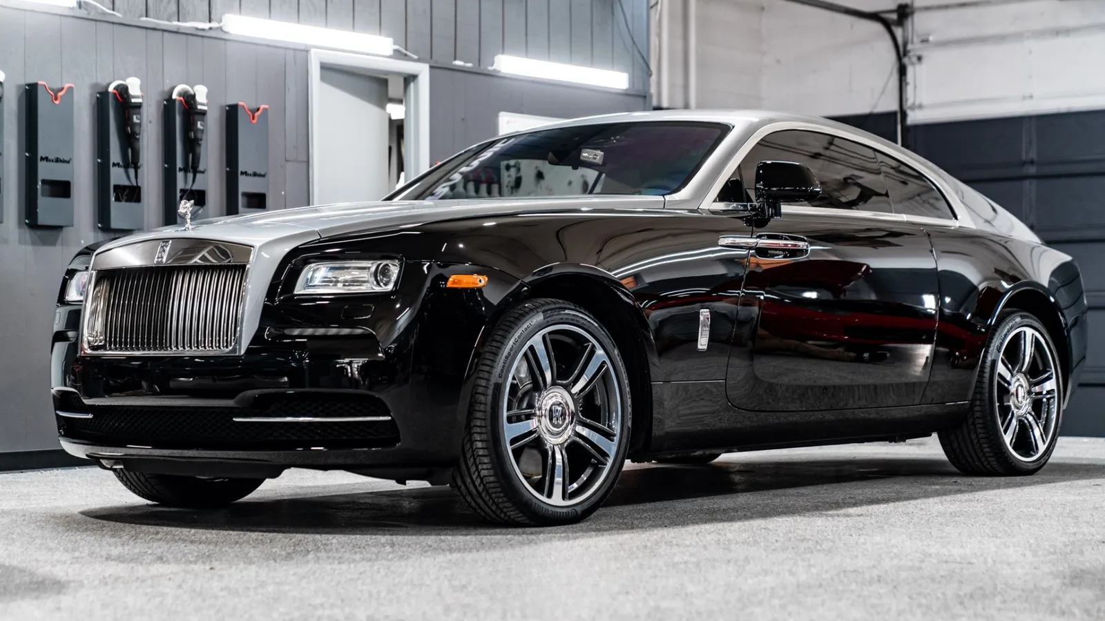 Black two-tone Rolls-Royce Wraith side profile in the shop, mirror-finish gloss paint