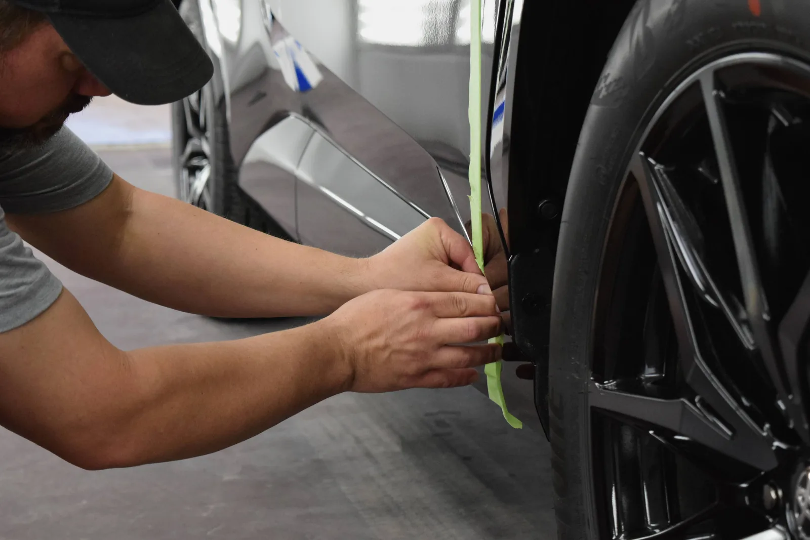 Heritage technician masking a wheel arch with green automotive tape before PeelClear application
