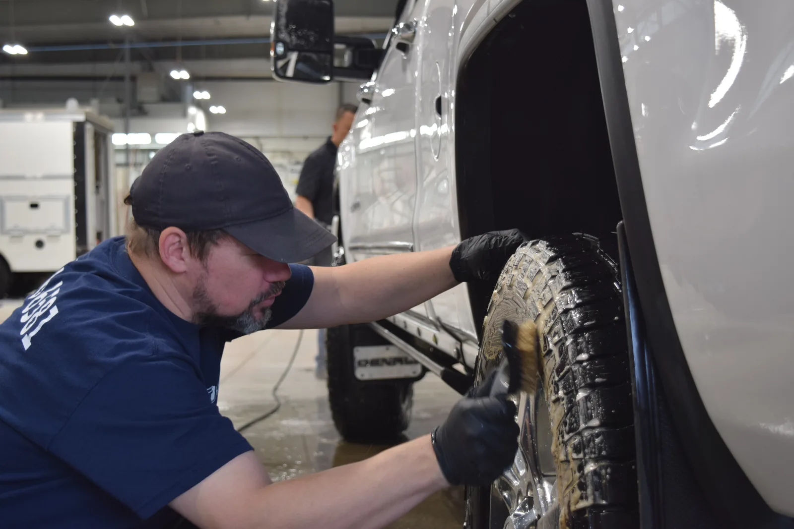 Heritage technician detailing tire sidewall with a brush during pre-spray preparation
