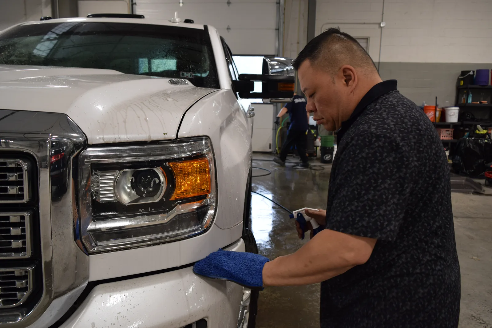Heritage technician hand-washing a white GMC pickup truck during decontamination prep