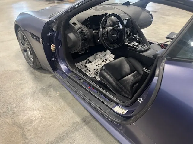 Matte navy Jaguar F-Type with driver door open showing black interior, color-change PeelClear visible on door jamb